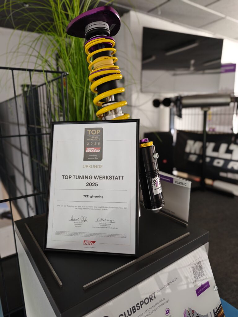 Gerahmte Urkunde TOP Tuning-Werkstatt 2025 in der Werkstatt, davor ein KW-Clubsport-Gewindefahrwerk